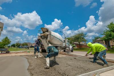 Concrete truck pouring new driveway from the right of way with construction workers