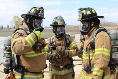 3 volunteer firefighters in yellow coats and breathing masks
