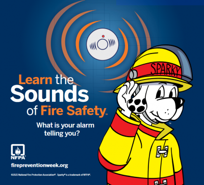 Fire Prevention graphic showing Saprky the fire dog dressed in a yellow jacket listening to a fire alarm