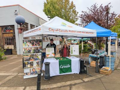 Budget Gap outreach The Mayor and City Councilors behind a display table on a street corner at the Corvallis Farmers Market.
