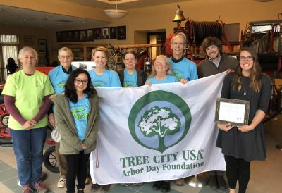 Neighborhood tree stewards posing with a big while Arbor Day flag