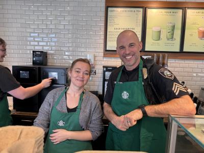 A Starbucks barista and a police officer, both wearing aprons during Coffee with a Cop
