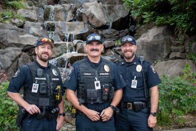 Three police officers stand in front of a landscaped water feature