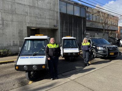 Two parking enforcement scooters and two parking enforcement officers outside in front of the police station