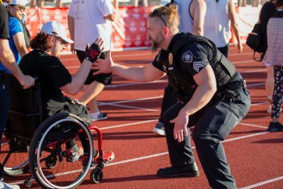 A police sergeant high fives a special olympics participant who is in a wheelchair