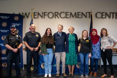 Award Photo A group of people stand in front of a Corvallis Police Department sign
