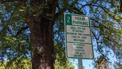 Residential parking permit sign on a post with a tree in the background