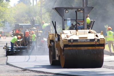 Steam roller laying down asphalt on a city street