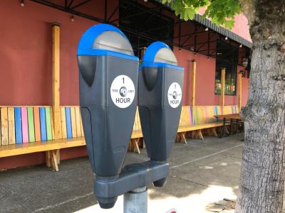 Parking meter on the sidewalk next to a rainbow colored restaurant facade.