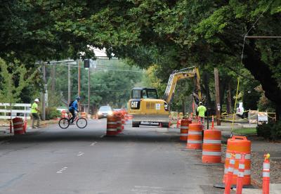 Road construction on Van Buren with orange barrels and a yellow excavator in the middle distance.