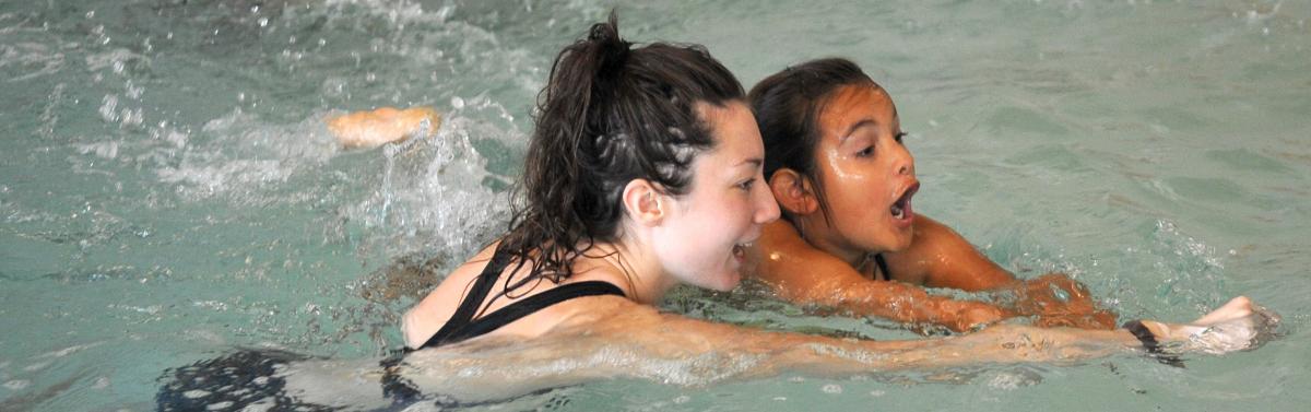 a swim instructor helping a child swim across the pool