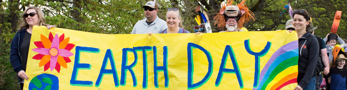 Five people holding a decorated Earth Day banner at the front of the Planet Palooza parade
