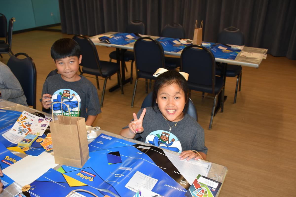 Family Fun Night showing two children doing crafts at a table. One holds up a peace sign for the camera
