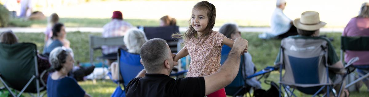 Young child dancing with father in park