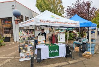 Budget Gap outreach The Mayor and City Councilors behind a display table on a street corner at the Corvallis Farmers Market.